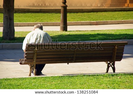 Ancient old man sitting on a bank of a public park