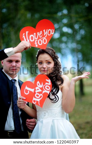 happy Groom and Bride in a park with signs I Love You . wedding dress. Love.