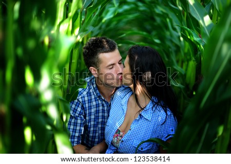 Romantic young couple sitting together in cornfield and kissing. love story.