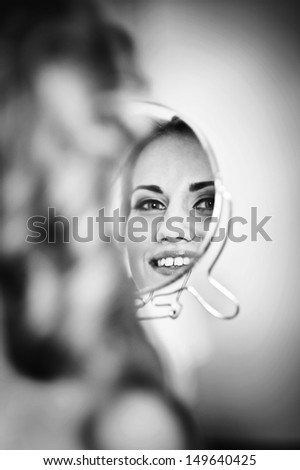 Happy beautiful bride  girl in white wedding dress with hairstyle and bright makeup at home background looking in the mirror