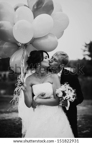 cheerful wedding couple with colorful balloons in the park having fun