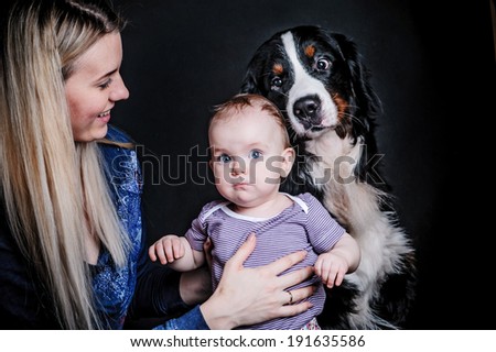 Portrait of loving mother and her child on black background with big dog