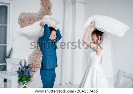 Portrait of happy newlywed couple fighting with pillows