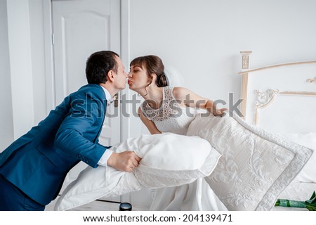 Portrait of happy newlywed couple fighting with pillows