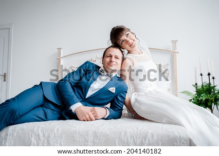 bride and groom lying on the bed. kiss and hug each other