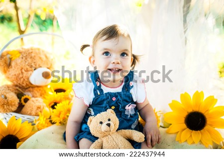 Summer portrait of beautiful baby girl with sunflowers in park.photo zone is decorated with sunflowers and bees.