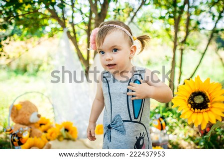 Summer portrait of beautiful baby girl with sunflowers in park.photo zone is decorated with sunflowers and bees.