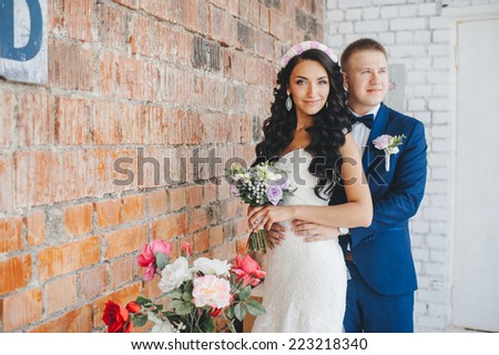 cute wedding couple in the interior studio decorated red brick. hey kiss and hug each other