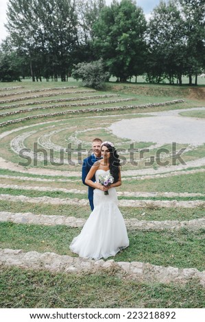 Wedding shot of bride and groom in park. summer nature outdoor. Beautiful bride and groom is enjoying his wedding day. They kiss and hug each other