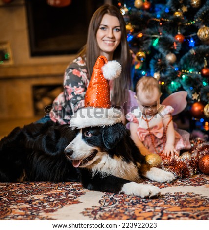 Little girl being happy about christmas tree and lights with mom and dog