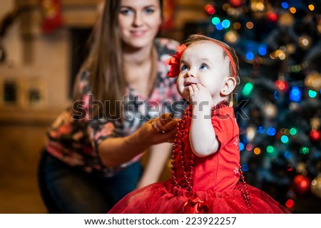 Little girl being happy about christmas tree and lights with mom