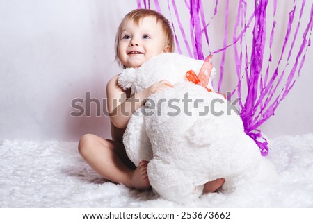 portrait of adorable smiling girl with bear toy on white and purple decorations background