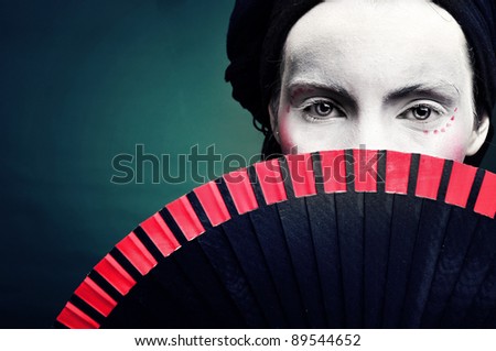 portrait of a strange woman mime or a clown with a fan and bodypainting