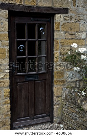 Old cottage door in England with blown glass in the window panes and roses blooming at the door