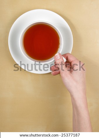 tea - top view female hand holds a cup of tea on wood table