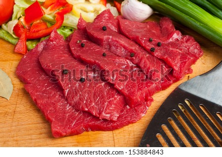 strict beef steaks on the board with vegetables in the background