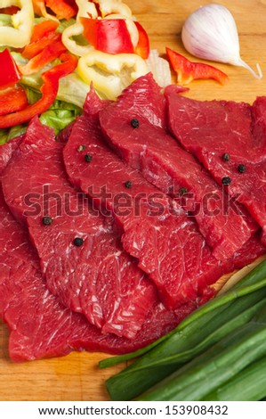 strict beef steaks on the board with vegetables in the background