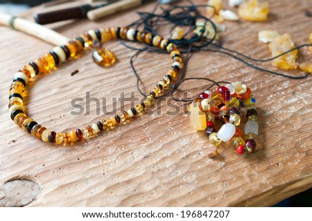 Hand-made ??necklace using simple tools of ancient amber and colored glass  - in the background tools.