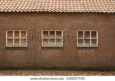Old wall with windows, windows have been covered with wooden panels