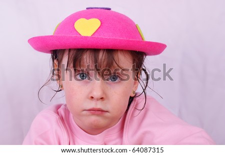 Sad, uninterested girl with a happy pink hat