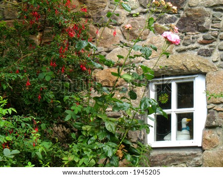 Quaint stone cottage wall with flowers and window