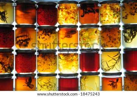 Jelly jars full of preserves sitting on window ledge backlit by sun.