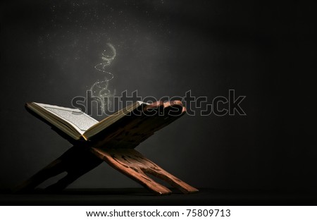 A still-life image of Koran (Holy Book of Muslims) on dark black background, with sprinkles falling on.