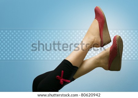 Attractive feet high up, showing red polka dotted shoes, against a vignette blue background with polka dots.