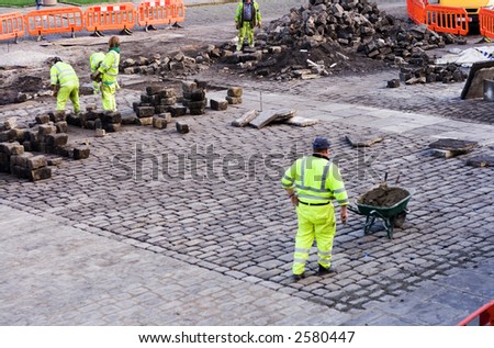 Workmen wearing fluorescent jackets laying cobbles in Piece Hall, Halifax West Yorkshire