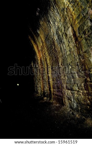 Dark brickwork textures of wall. Underground Light painting in disused railway tunnels, darkness creatively lit with torches.