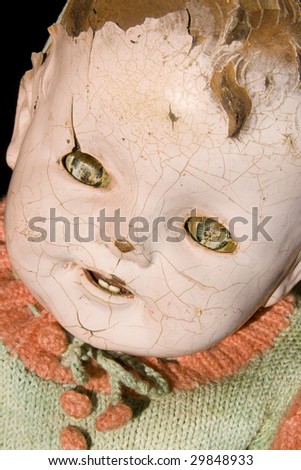 Old antique child doll with creepy face, cracked and worn, has seen better days.