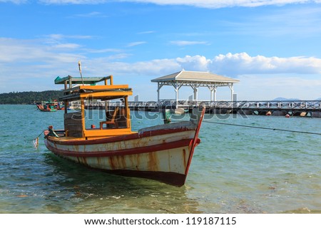 Wooden boat parking in the tropical sea with walk bridge in background