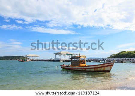 Wooden boat parking in the tropical sea with walk bridge in far background