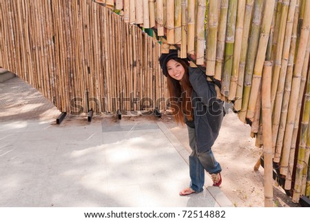 young woman is bending under bamboo arch and smile with relax feeling