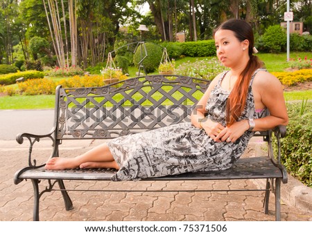 distracted Asian women lay down on bench in park