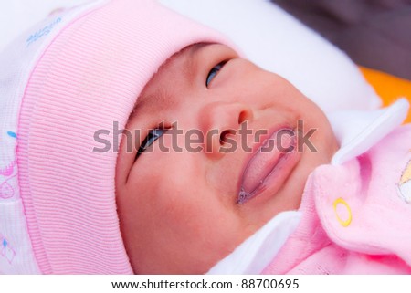 Asian new born in pink dress start crying on bed