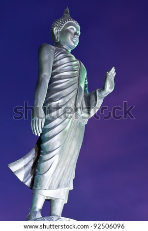 Back of walking Buddha statue with blue sky in twilight tilted
