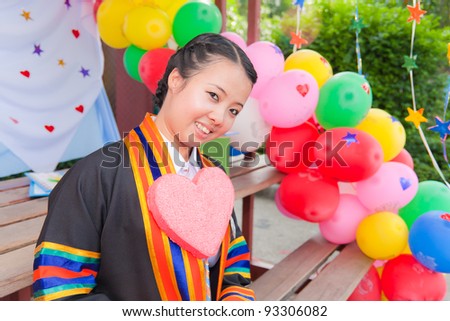 Graduated Asian girl with Pink heart and colorful balloons in background