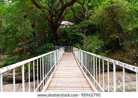 Wooden bridge with metal hand rail cross river in forest