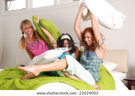 Three young women having fun (pillow fight) Blonde, Brunette and a Redhead