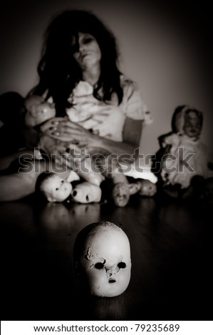Creepy Doll Head with Possessed Woman holding doll parts in the background Focus is on doll head