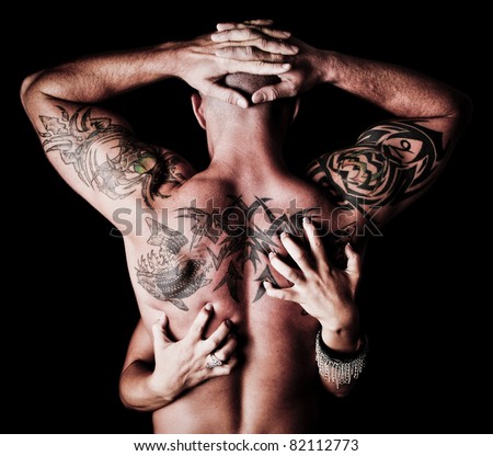 Back of a Man with tattoos with a woman\'s hands scratching his back