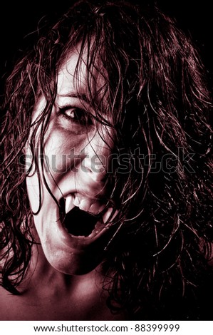 Vampire with long wet hair, fangs and red eyes ready to feed in the night