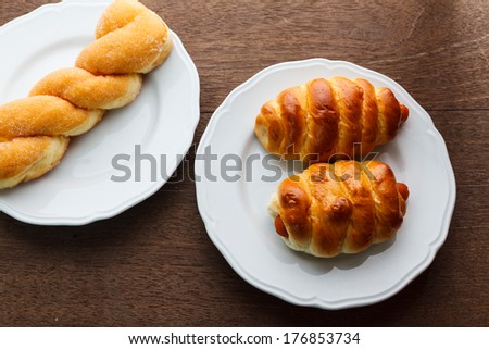 Bread roll and Bread sausage on dish with wooden background.
