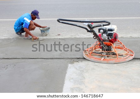 MAHASARAKHAM, THAILAND - JULY 13 : Unidentified man is spreading concrete floor and working hard at Mahasarakham - Roi Et road on July 13, 2013 in Mahasarakham, Thailand.