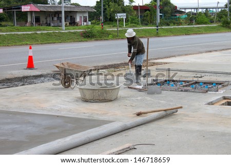 MAHASARAKHAM, THAILAND - JULY 13 : Unidentified man is spreading concrete floor and working hard at Mahasarakham - Roi Et road on July 13, 2013 in Mahasarakham, Thailand.