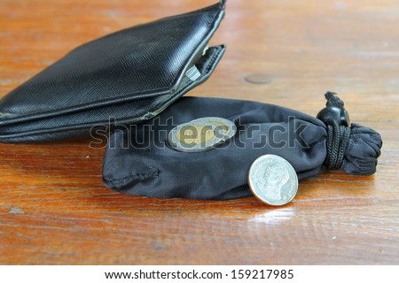 coins out of a leather purse on teak table