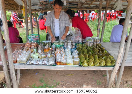 MAHASARAKHAM - AUGUST 6 : Unidentified man hawker is preparing take away foods for sell at Tha Rae Wattana village market stall on August 6, 2013 in Mahasarakham, Thailand.