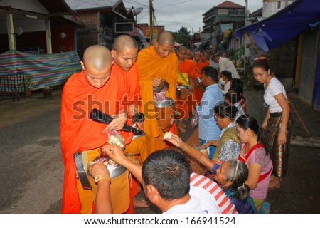 VANG VIENG, LAO P.D.R. - AUGUST 25 : Monks ask for alms at traditional morning market on August 25, 2013 in Vang Vieng, Lao P.D.R.