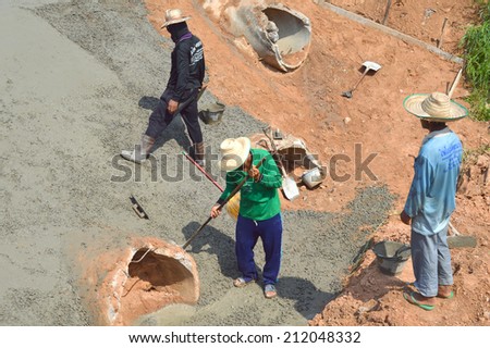 MAHASARAKHAM, THAILAND - MAY 15 : Masonry workers repair sanitary sewer and concrete floor at Mahasarakham - Roi Et bypass road on May 15, 2014 in Mahasarakham, Thailand.